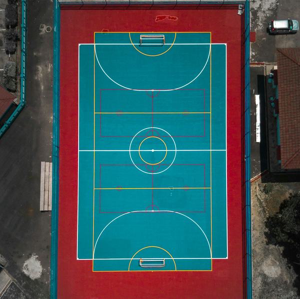 Aerial view of a teal and red outdoor futsal court surrounded by buildings in Kuantan